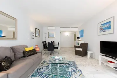 a living room with a couch and a glass table at Palm Beach 3 chambres in Cannes
