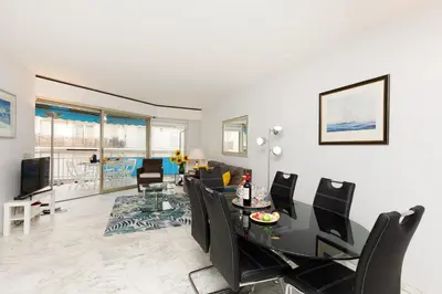 a dining room and living room with a table and chairs at Palm Beach 3 chambres in Cannes