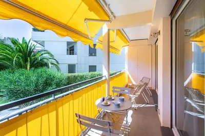 a balcony with a table and chairs on a yellow wall at C9 - 2 BDR 10 min Palais Festivals & Sea - AC, Parking & Balcony in Cannes