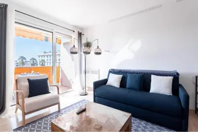 a living room with a blue couch and a table at Cocoon with garden near the sea in Cannes