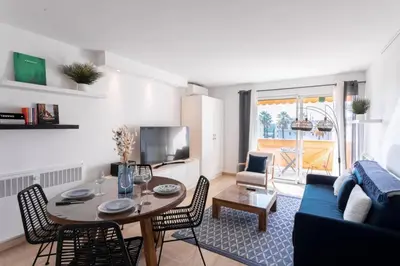 a living room with a table and a blue couch at Cocoon with garden near the sea in Cannes