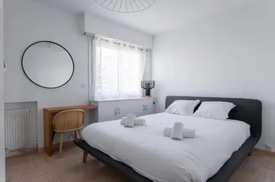 a bedroom with a large white bed and a mirror at Cocoon with garden near the sea in Cannes