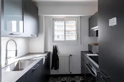 a white kitchen with a sink and a window at Cocoon with garden near the sea in Cannes