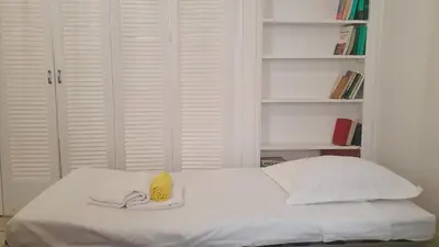 a white bed with a yellow hat on top of it at Bel Appartement Typique proche du Palais et Plages in Cannes
