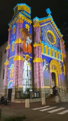 a building with a clock tower lit up at night at Bel Appartement Typique proche du Palais et Plages in Cannes
