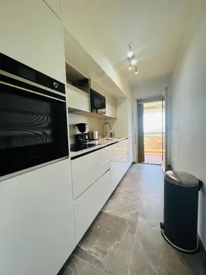 a kitchen with white cabinets and a black microwave at Les yeux dans le bleu, Cannes Vue mer in Cannes