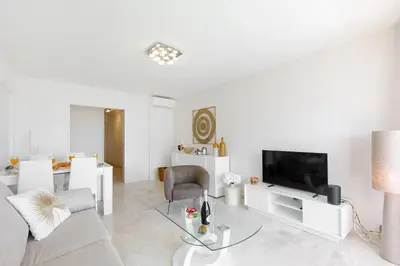 a white living room with a couch and a tv at Royal Palm YourHostHelper in Cannes