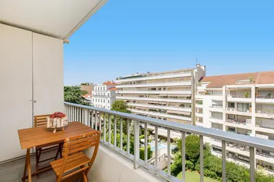 a balcony with a wooden table and a view of buildings at Royal Palm YourHostHelper in Cannes