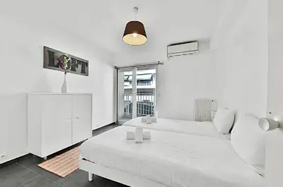 a white bedroom with a white bed and a window at LE VERSAILLES plaisir et confort en centre-ville, pour séjours en famille ou business in Cannes
