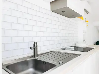a kitchen with a sink and white tiled walls at Le Bardot Croisette - Proche Palais & Mer - Climatisation in Cannes
