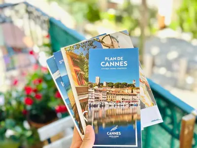 a person holding two brochures in their hand at Place du Suquet - Terrasse - 3 Chambres - Parking in Cannes