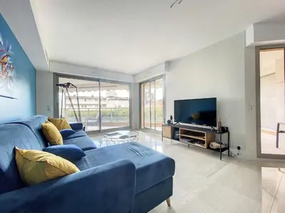 a living room with a blue couch and a tv at Cannes - Basse Californie - 3 pièces in Cannes
