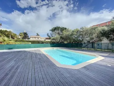 a swimming pool on a wooden deck next to a house at Cannes - Basse Californie - 3 pièces in Cannes