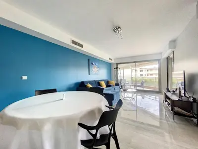 a living room with a table and a blue wall at Cannes - Basse Californie - 3 pièces in Cannes