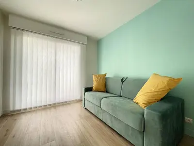 a living room with a green couch with yellow pillows at Cannes - Basse Californie - 3 pièces in Cannes