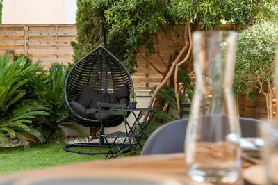 a black swing chair sitting in a garden at Cozy 1-Br Apartment heart of Palm Beach district in Cannes