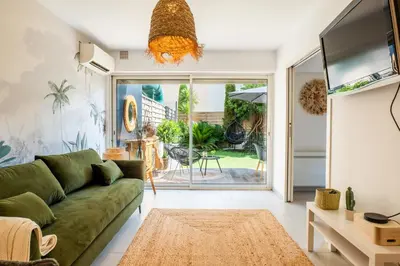 a living room with a green couch and a tv at Cozy 1-Br Apartment heart of Palm Beach district in Cannes
