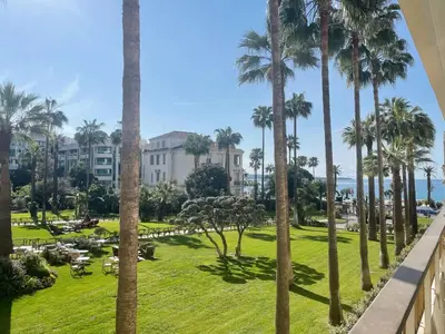 a view of a park with palm trees and a building at Studio Cannes Grand Hôtel Cormoran avec Terrrasse in Cannes