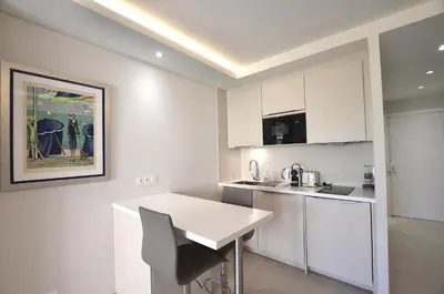 a kitchen with white cabinets and a white table at Studio Cannes Grand Hôtel Cormoran avec Terrrasse in Cannes