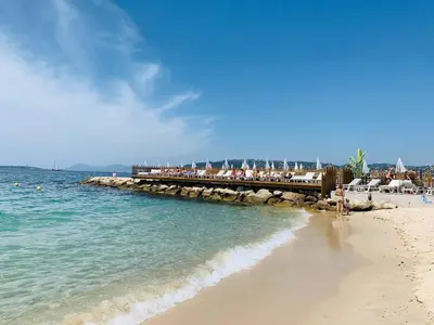 a beach with a pier and the ocean with people on it at Splendid 1 bedroom and 1 sofabed renovated 2P3 by RIVAEVENT in Cannes