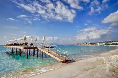 a pier with chairs and umbrellas on a beach at Splendid 1 bedroom and 1 sofabed renovated 2P3 by RIVAEVENT in Cannes