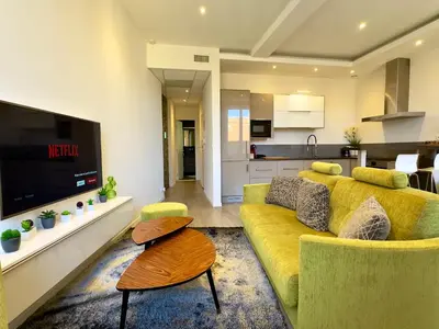 a living room with a yellow couch and a kitchen at Eleganza By SCLS Locations in Cannes