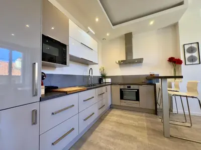 a kitchen with white cabinets and a table in it at Eleganza By SCLS Locations in Cannes