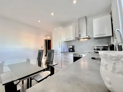 a kitchen with white cabinets and a table with chairs at HENRY IV 2 pieces MES1112 in Cannes