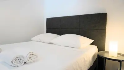 a bed with white pillows and a black headboard at Centre Cannes, Le Grand Turkheim By Palmazur Vacances in Cannes