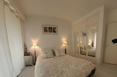 a white bedroom with a bed and two lamps at Cannes centre beau 2 pièces 50 M2 plus terrasse à 12 min plages et Palais au calme in Cannes