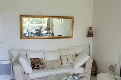 a living room with a white couch and a mirror at Cannes centre beau 2 pièces 50 M2 plus terrasse à 12 min plages et Palais au calme in Cannes