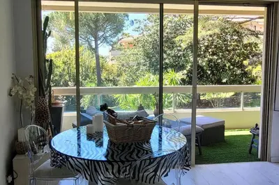 a living room with a table and a large window at Cannes centre beau 2 pièces 50 M2 plus terrasse à 12 min plages et Palais au calme in Cannes