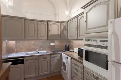a kitchen with white cabinets and a sink and a dishwasher at Le Château Vallombrosa by Halldis in Cannes