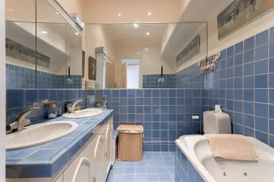 a blue tiled bathroom with two sinks and a toilet at Le Château Vallombrosa by Halldis in Cannes