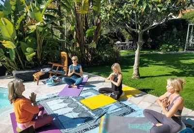 a group of women sitting in a yoga pose by a pool at Blue Dream Cannes Guest House in Cannes