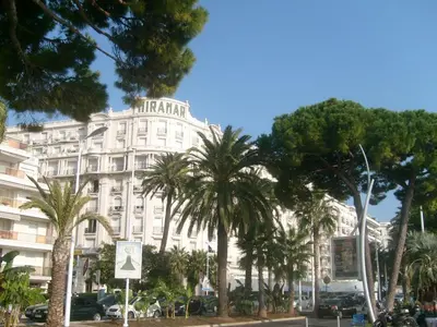 a large white building with palm trees in front of it at Studio Croisette in Cannes