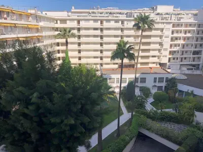 a large white building with palm trees in front of it at Studio Croisette in Cannes