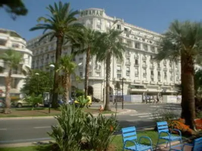 two blue chairs in front of a building with palm trees at Studio Croisette in Cannes