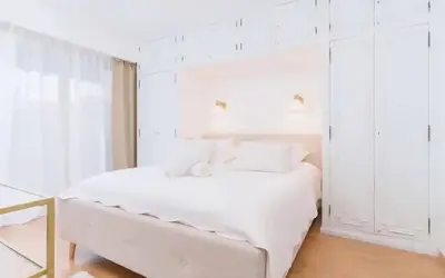 a white bedroom with a white bed and white cabinets at Le Concorde - Charmant appt avec terrasse in Cannes