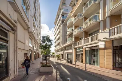 a woman walking down a street next to buildings at PLEIN SUD - le tapis rouge Croisette in Cannes