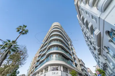 a tall building with a palm tree in front of it at PLEIN SUD - le tapis rouge Croisette in Cannes