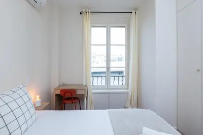 a white bedroom with a bed and a window at Villa CANA in Cannes