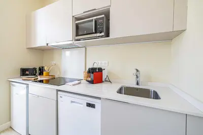 a white kitchen with a sink and a microwave at Quiet and luxurious studio - Cannes Center in Cannes