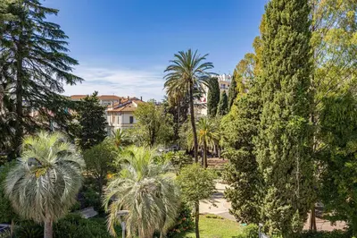 a garden with palm trees and buildings in the background at Quiet and luxurious studio - Cannes Center in Cannes