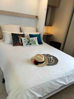 a hat sitting on top of a white bed at Tapualiki studio cosy tout confort in Cannes