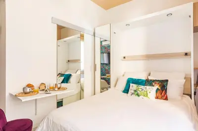 a bedroom with a white bed and a mirror at Tapualiki studio cosy tout confort in Cannes