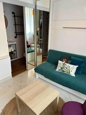 a living room with a green couch and a coffee table at Tapualiki studio cosy tout confort in Cannes
