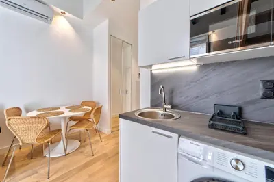 a kitchen with a sink and a table with chairs at Appartement Croisette Cannes centre in Cannes
