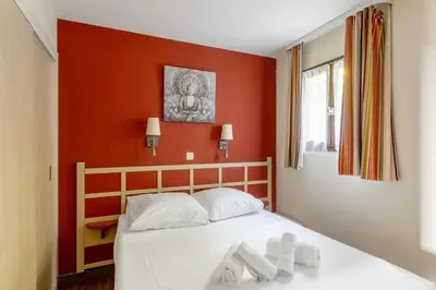 a bedroom with a white bed with red walls at Appartement Wemyssia - Welkeys in Cannes