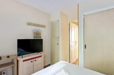a bedroom with a flat screen tv and a bed at Appartement Wemyssia - Welkeys in Cannes
